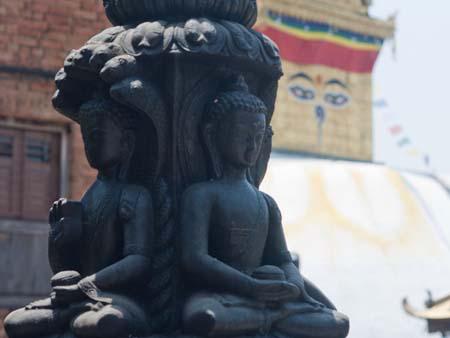 Stone Buddhas with the large stupa visible in the background