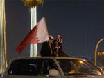 Children sticking out the sunroof with large flag